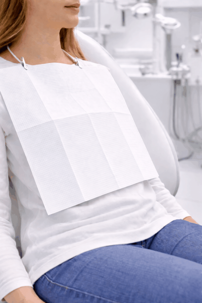 Paciente con un babero dental desechable blanco de tres capas